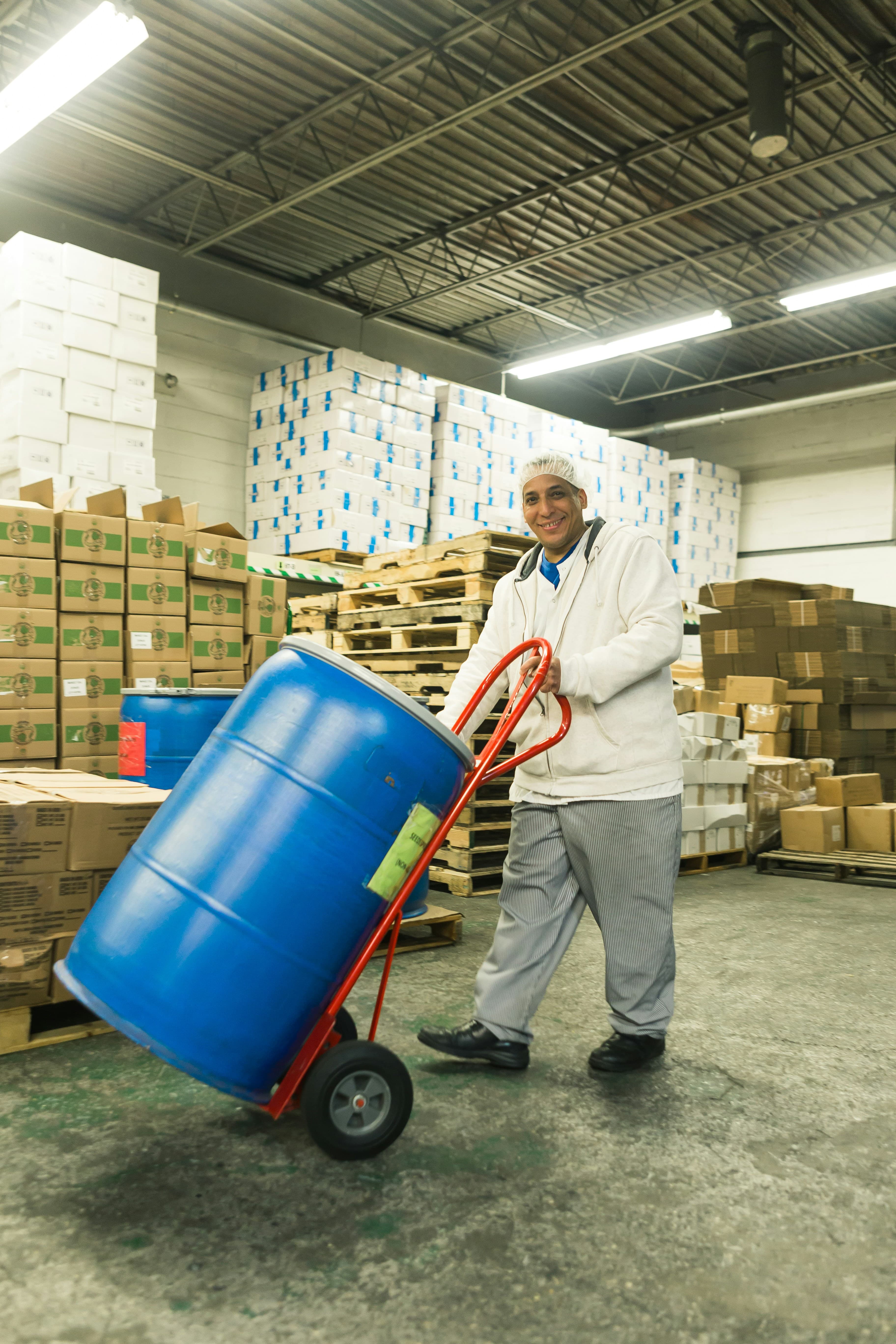 A warehouse worker moving stock past shelves of boxed inventory